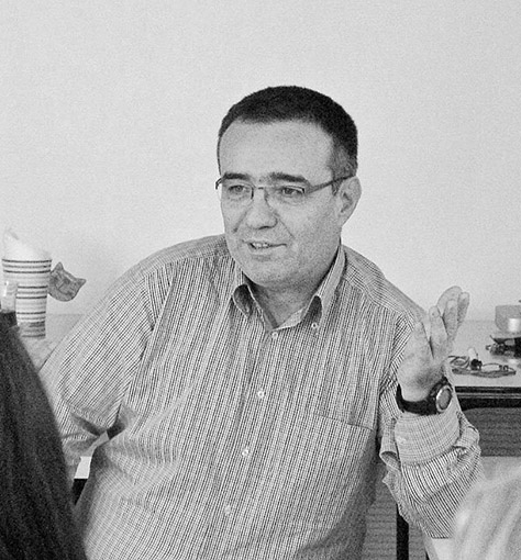 Tahir Un oturdugu yerden guleryuzle ve ellerini kullanarak konusrken cekilmis bir portre